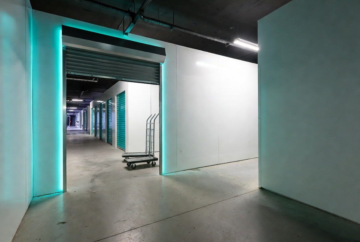 Wide bright hallway with teal neon doors at Storio